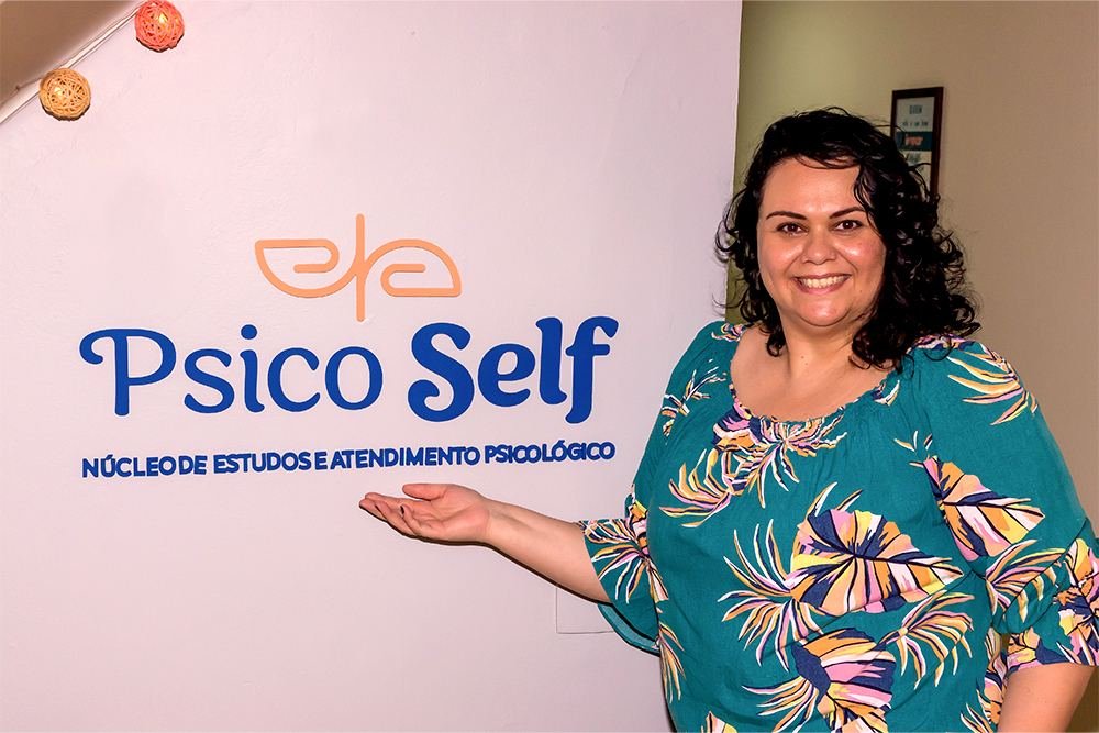 Luciana Furtado ao lado do logotipo da Psico Self pintado na parede